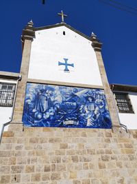 Low angle view of cross and building against clear blue sky