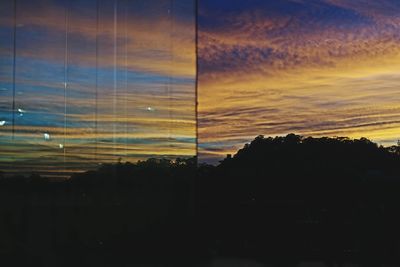 Silhouette trees against dramatic sky during sunset