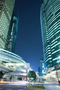 Illuminated modern buildings in city against clear sky at night