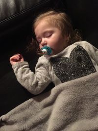 High angle view of toddler sleeping with pacifier on bed