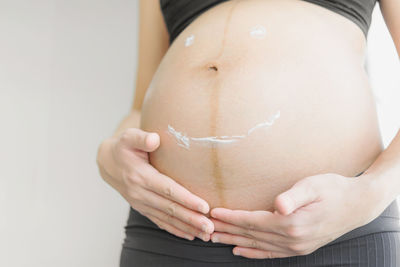 Close-up of woman holding hands over white background