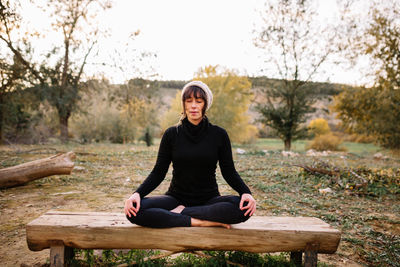 Woman practicing yoga and meditating on the park bench