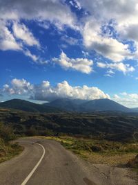 Country road along landscape against sky