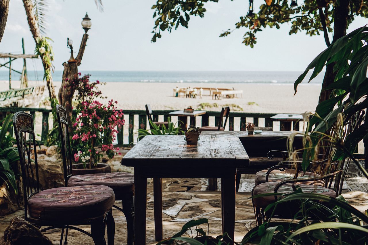 CHAIRS AND TABLE AT BEACH AGAINST SKY