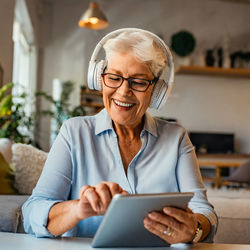 Grandma enjoying the music on her ipad using phone while sitting at home