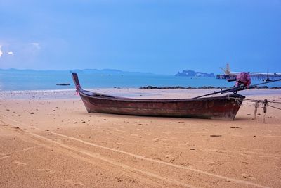 Boat moored on beach against sky