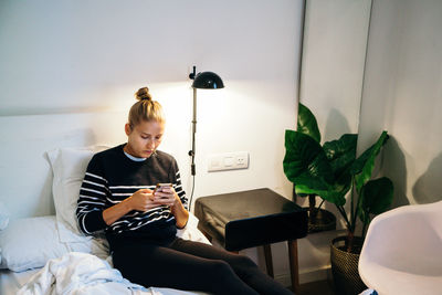 Woman using her phone when sitting on bed