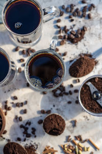 Still life with glass mugs of black hot coffee, coffee beans, ground coffee, making coffee at home