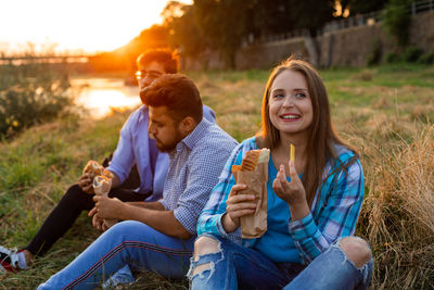 Friends eating food sitting at park