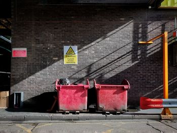 Couple of red bins on red brick background on street in city