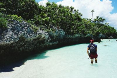 Rear view of man in sea by rock formation