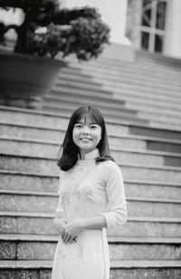 Portrait of smiling young woman standing on steps