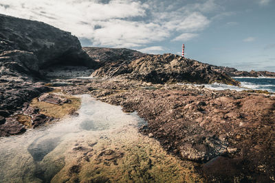 Lighthouse on the thing with a rocky landscape with a very calm natural pool