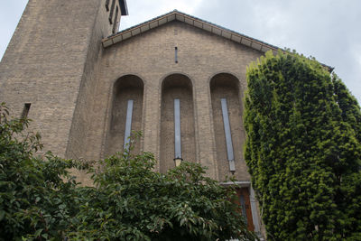 Low angle view of trees and building against sky