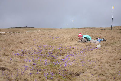 Rear view of woman working on field against sky