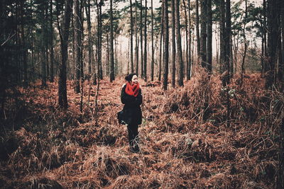 Full length of mid adult woman standing on field in forest