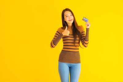 Portrait of woman standing against yellow background