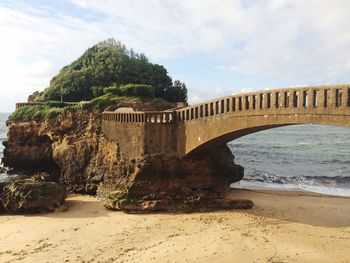 Bridge over sea against cloudy sky