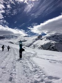 Woman practicing yoga while standing on snow against sky