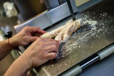 Cropped hand cutting meat on machinery