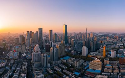 Aerial view of modern buildings in city against sky during sunset