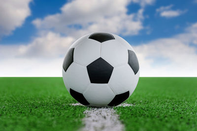 Digital composite of soccer ball on playing field against sky 