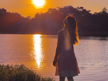 Rear view of woman standing at sunset