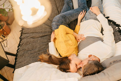 Rear view of friends lying on bed at home