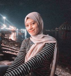 Portrait of smiling young woman in city at night