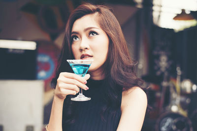 Close-up of thoughtful young woman holding martini glass in bar