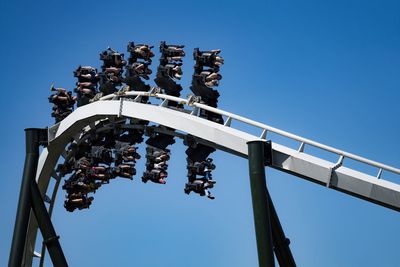 Low angle view of amusement park ride against blue sky