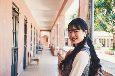 Portrait of smiling young woman standing in corridor