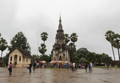 People visiting temple against sky in city