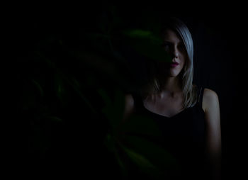 Portrait of young woman against black background