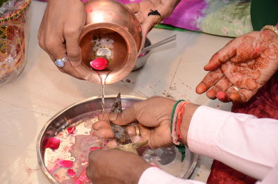 Cropped hands pouring water on knife during wedding ceremony