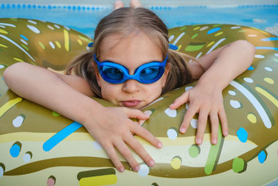 Portrait of young woman wearing sunglasses while sitting in swimming pool