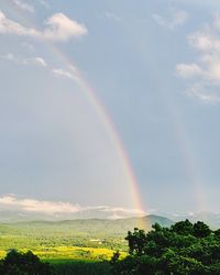 Scenic view of rainbow over landscape against sky