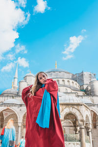 Low angle view portrait of woman standing against building