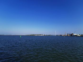 Sailboats in sea against clear blue sky