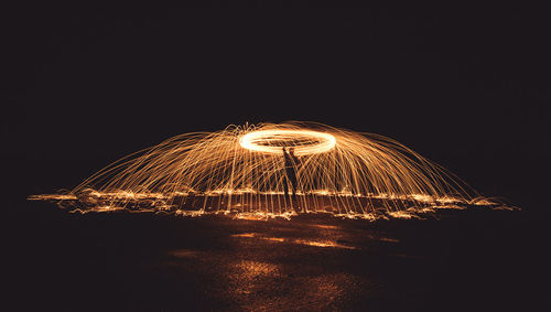 Illuminated ferris wheel against sky at night