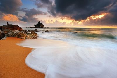 Sea against dramatic sky at sunset