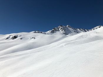 Scenic view of snowcapped mountains against clear blue sky