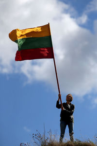 Low angle view of woman holding flag against sky