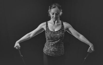 Woman exercising with resistance band against black background