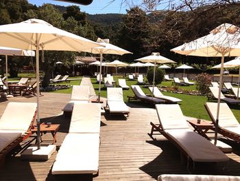 Chairs and tables on beach by swimming pool