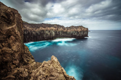 Rock formations in sea against sky