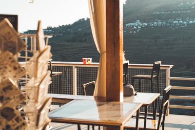Chairs and table in restaurant by sea against sky seen through window