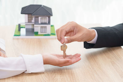 Close-up of man holding hands on table in house