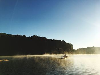 People in boat on river against blue sky