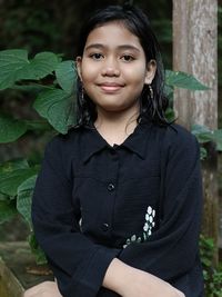 Portrait of young woman standing against plants